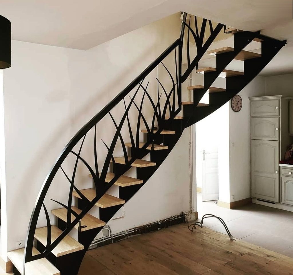 Escalier en acier noir à limon découpé en motif végétal, marches de bois.