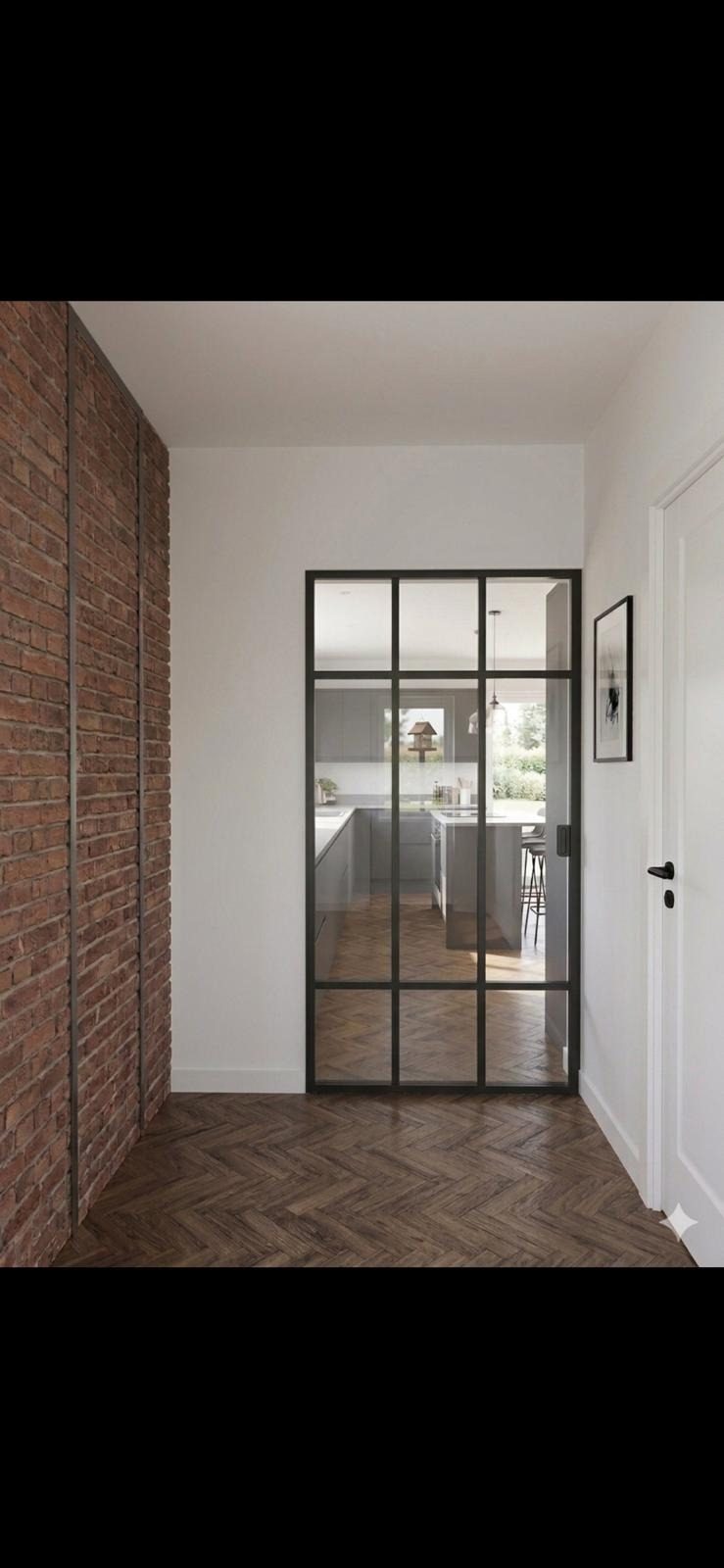Porte verrière à petits carreaux au bout d’un couloir clair, sol en chevrons.